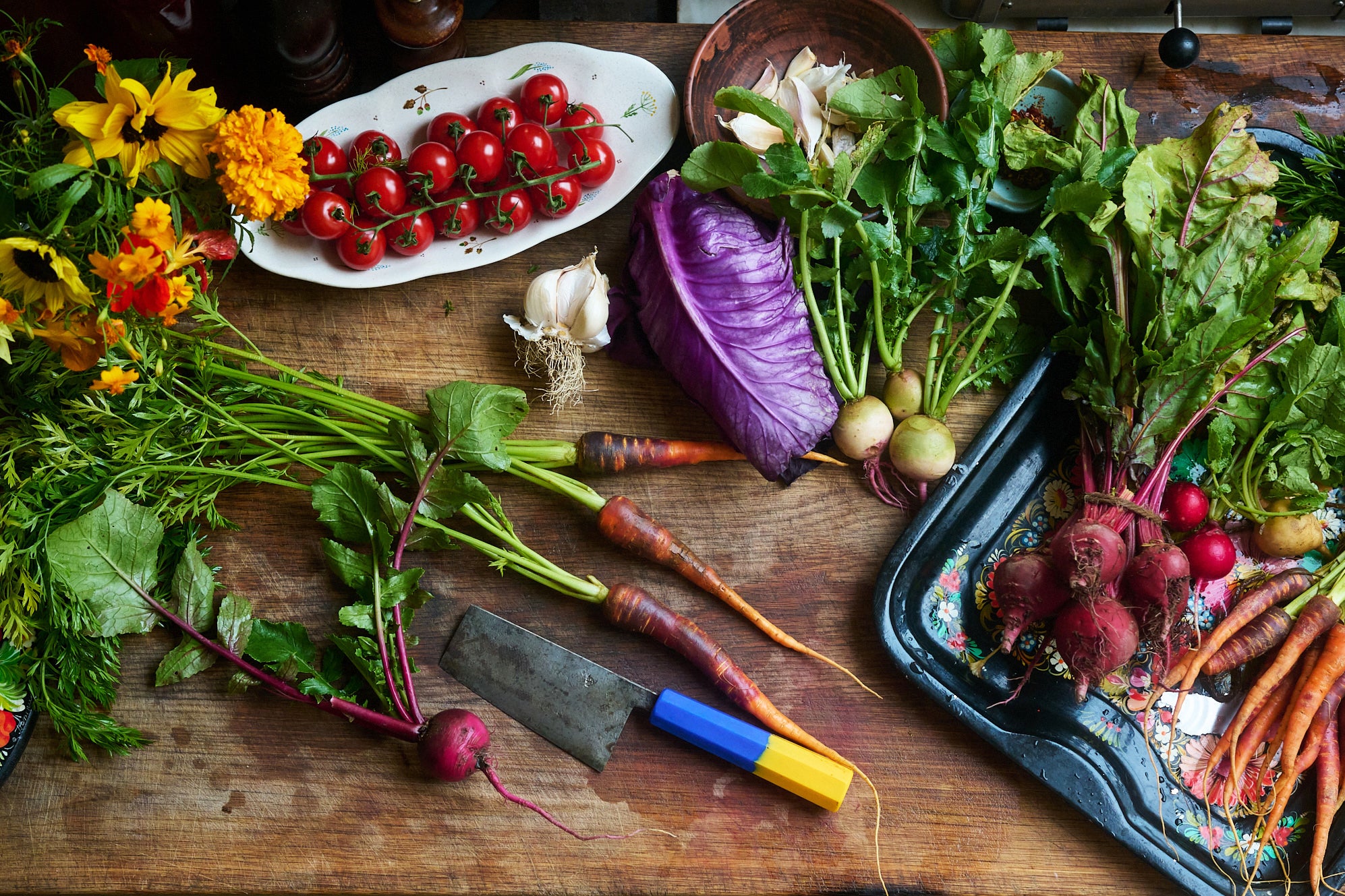 Colorful spring vegetables and a cleaver on a cutting board